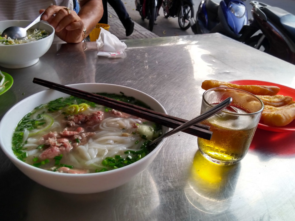 Bowl of pho bo at a simple eatery. Served with delicious fried bread for dunking. 