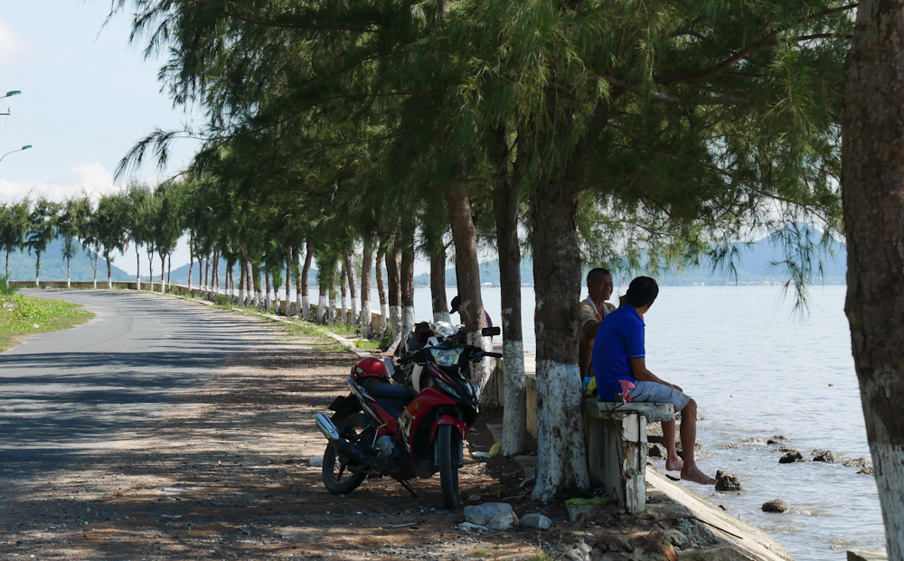 Locals relax on a seaside bench along Ha Tien's coast road. 