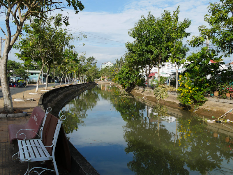 White benches next the the tree-lined Cai Son canal in Sa Dec. 